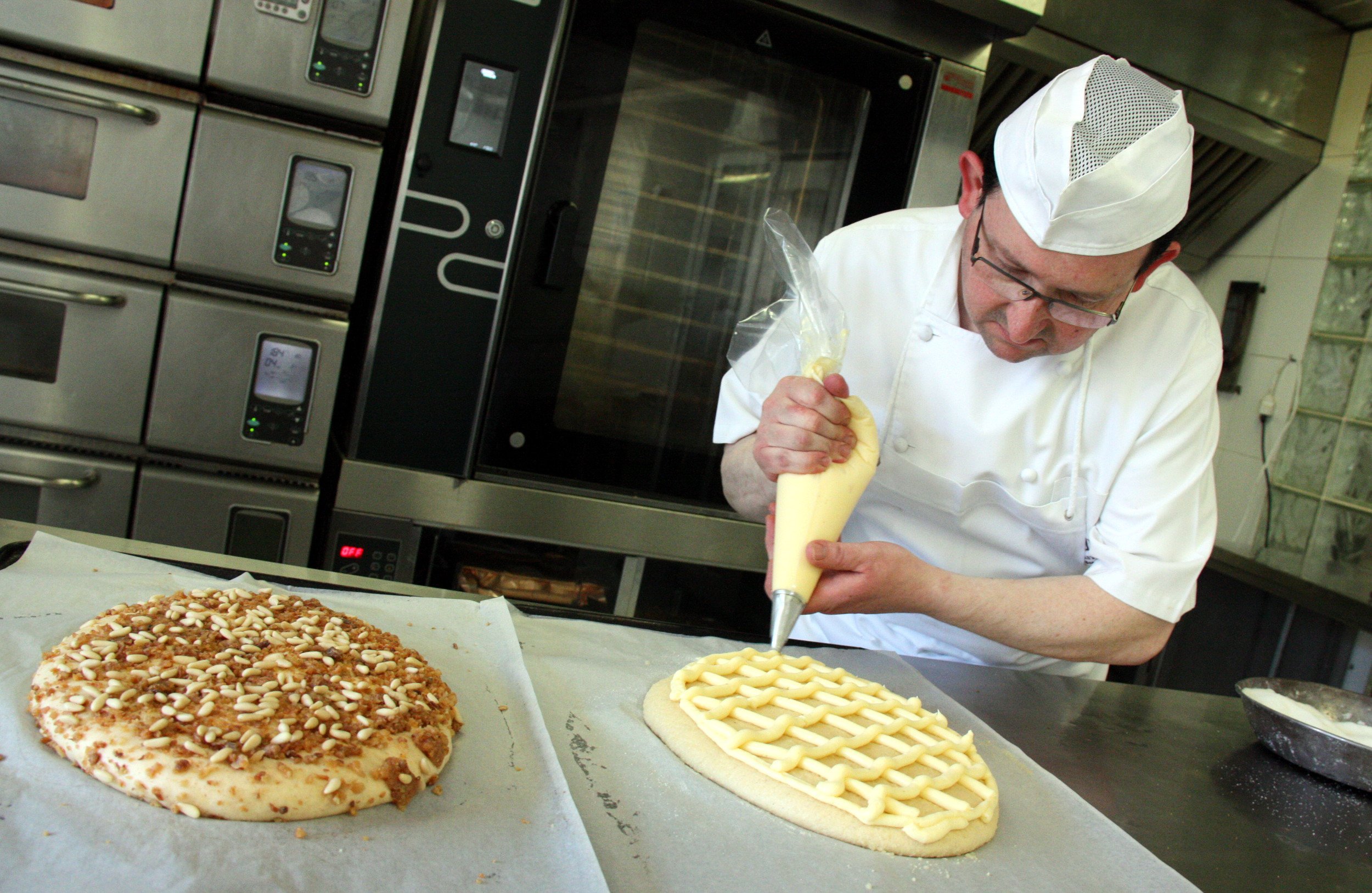 El pastisser Elies Miró col·loca la crema a una de les coques abans de coure-la al forn