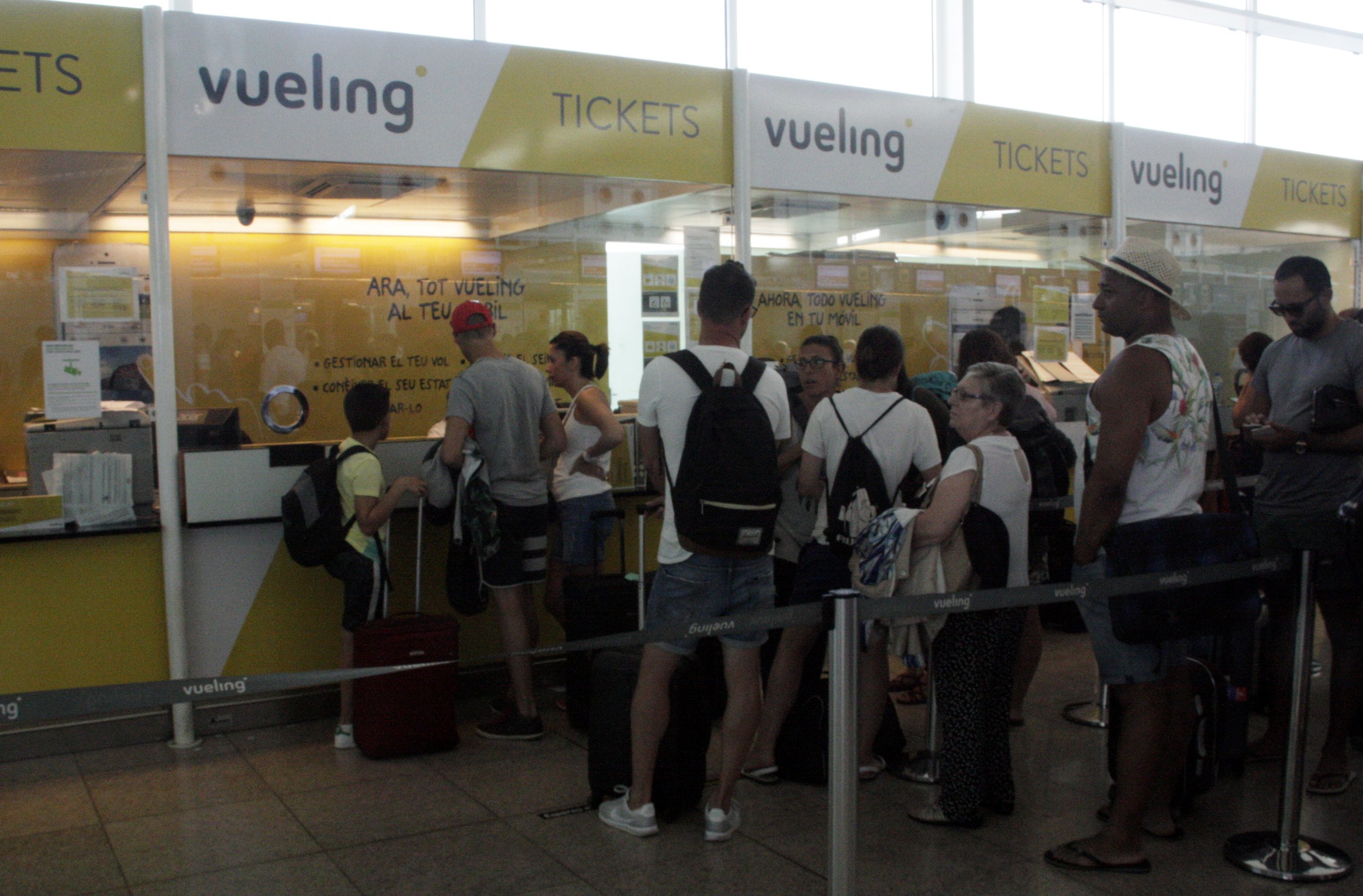 Passatgers als taulells d'atenció al cient de Vueling a l'aeroport del Prat aquest dilluns 