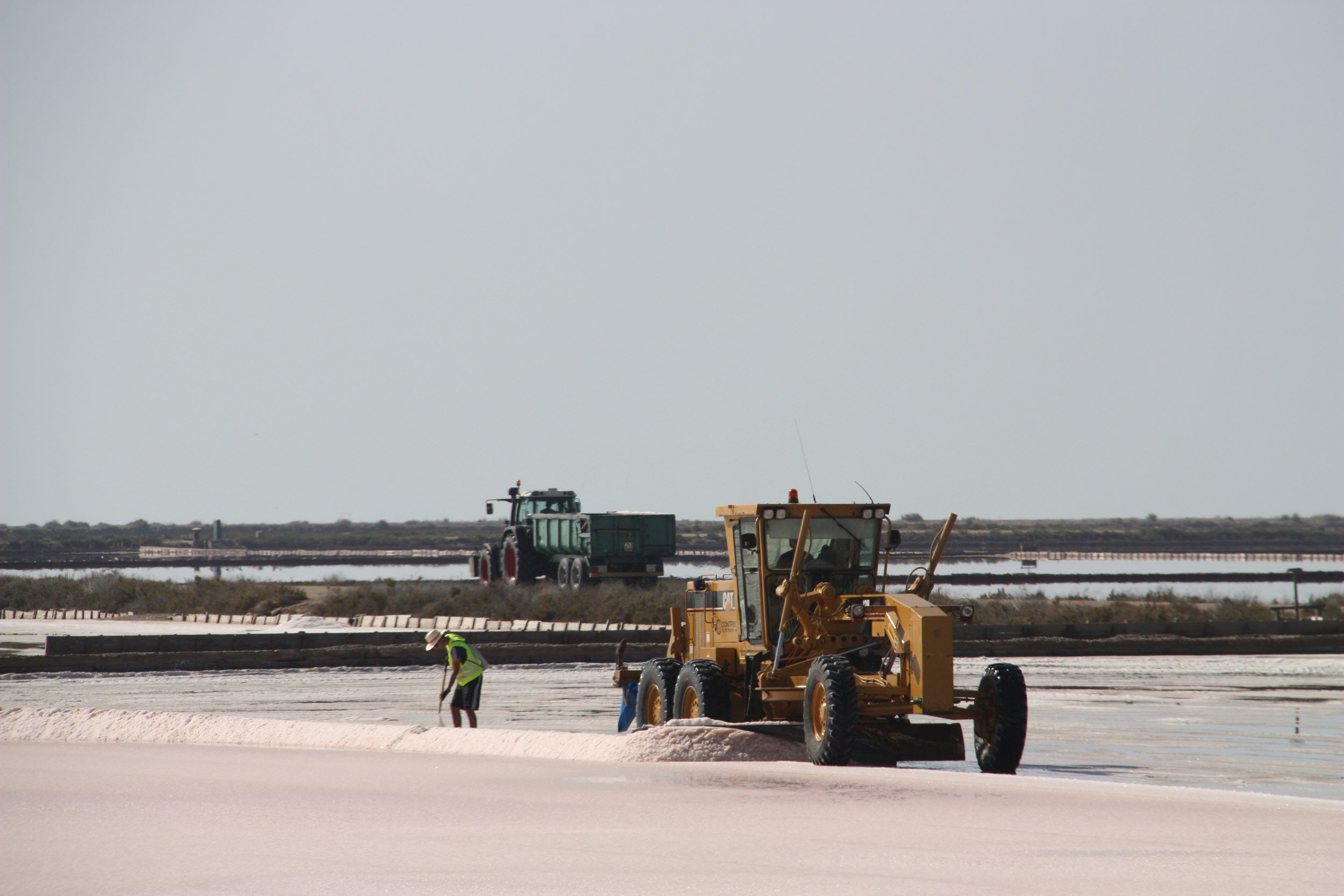 Un treballador d'Infosa treballant al costat d'un tractor a les Salines de la Trinitat 