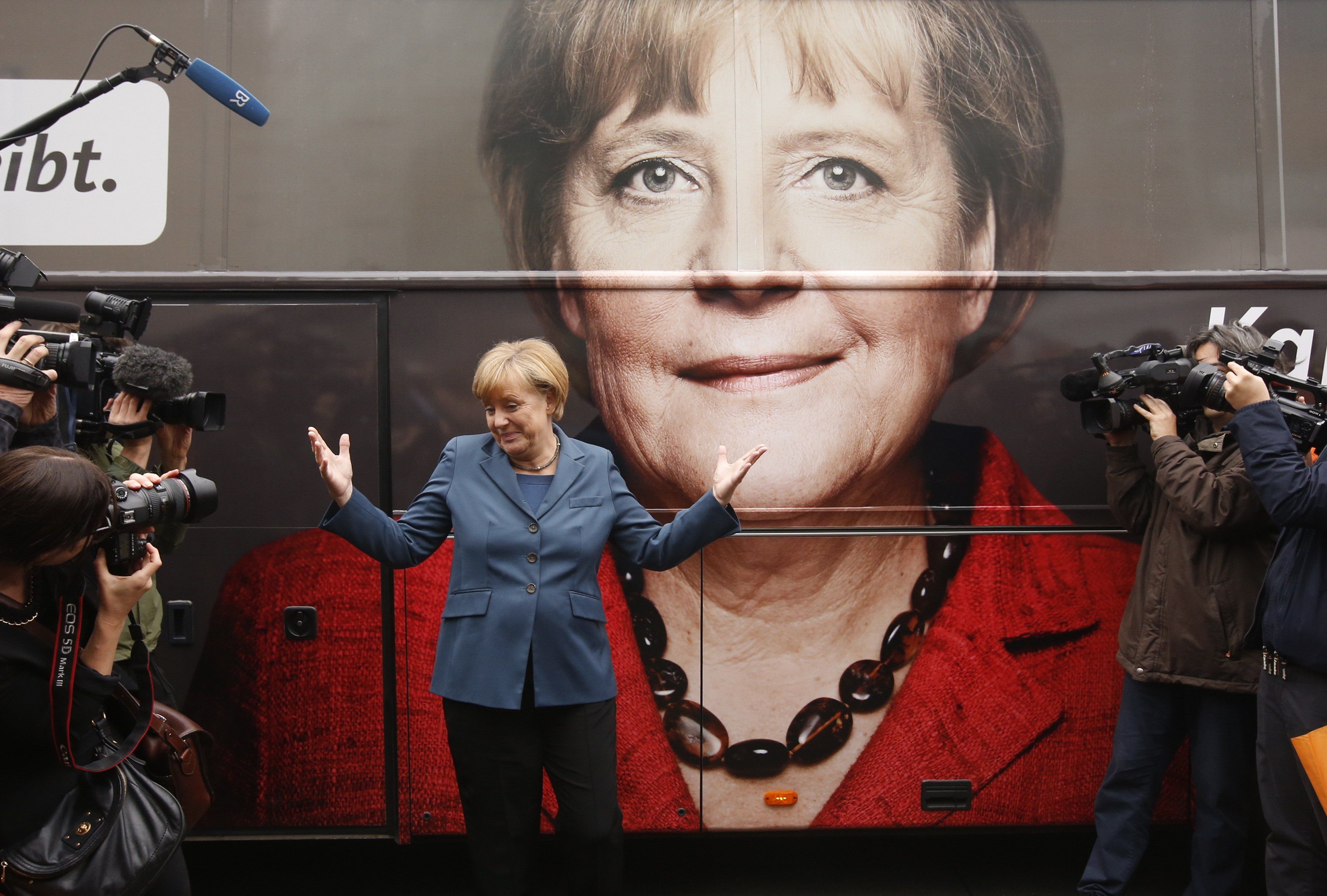 German chancellor, Angela Merkel, poses for photographs in front of an electoral campaign poster