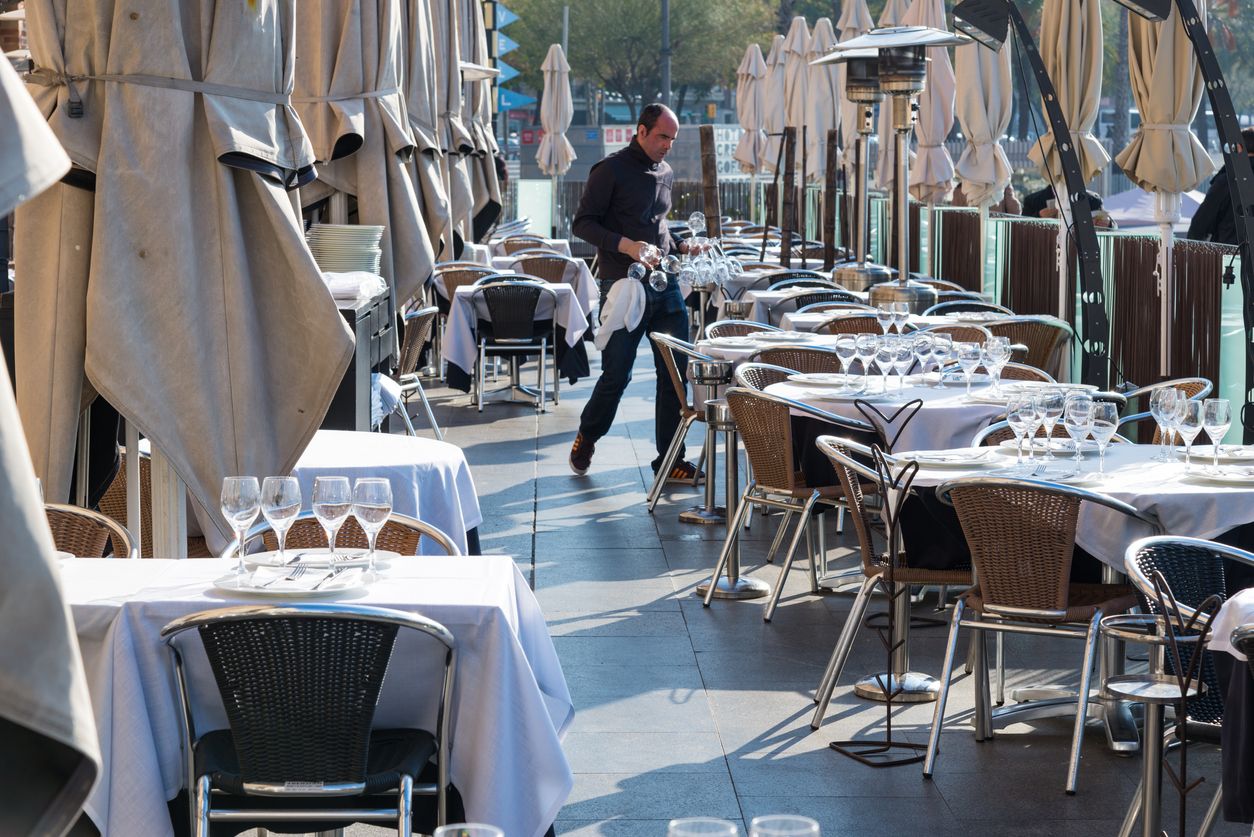 Un cambrer prepara taules en un restaurant davant del Palau de Mar | iStock