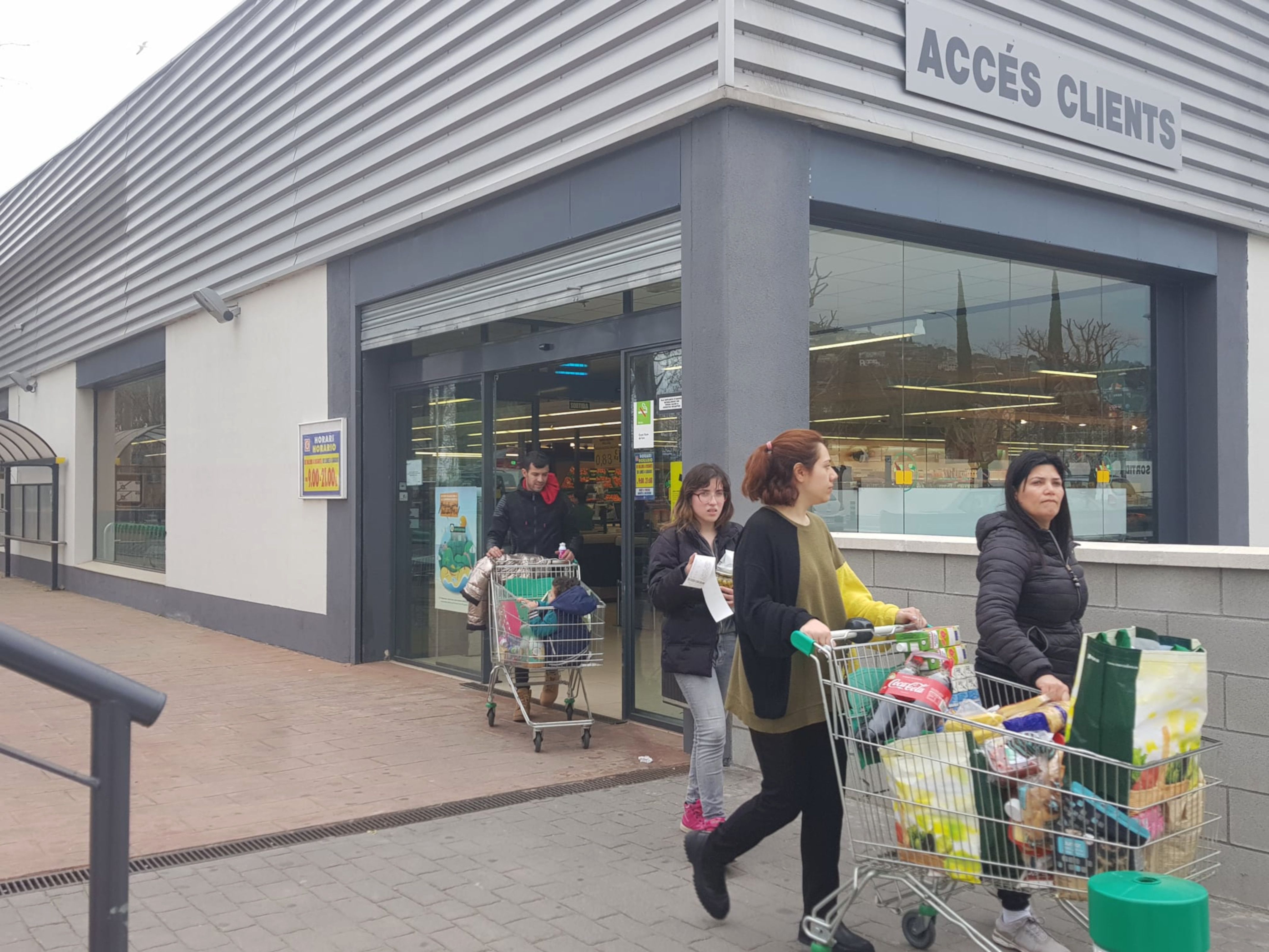 Unes clientes d'un supermercat sortint amb un carro de la compra | ACN