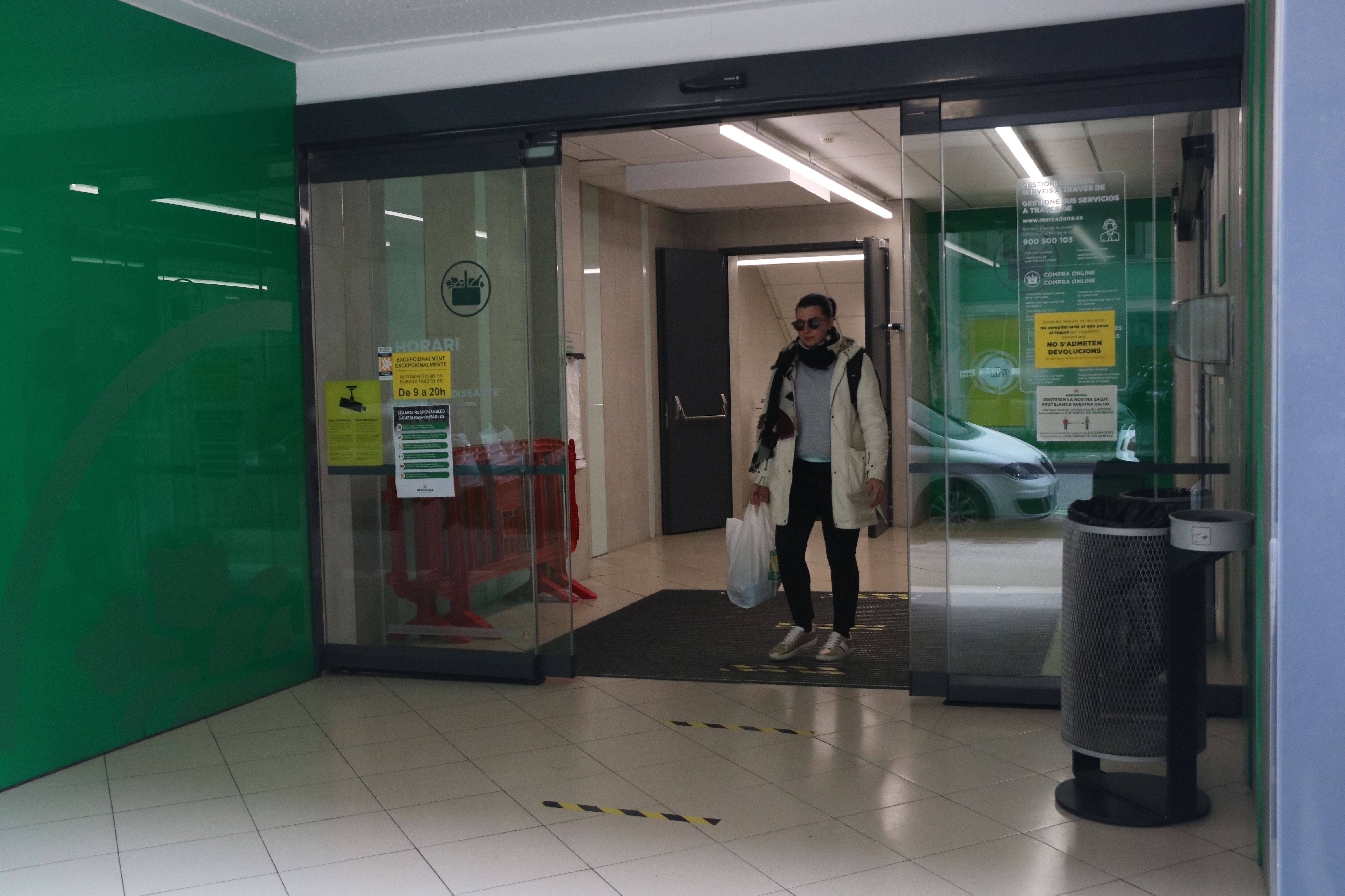 Cliente saliente de un supermercado Mercadona. En el tierra de la entrada, la cadena ha dibujado unas líneas porque los compradores respeten la distancia de seguridad | ACN (A. Cadanet)