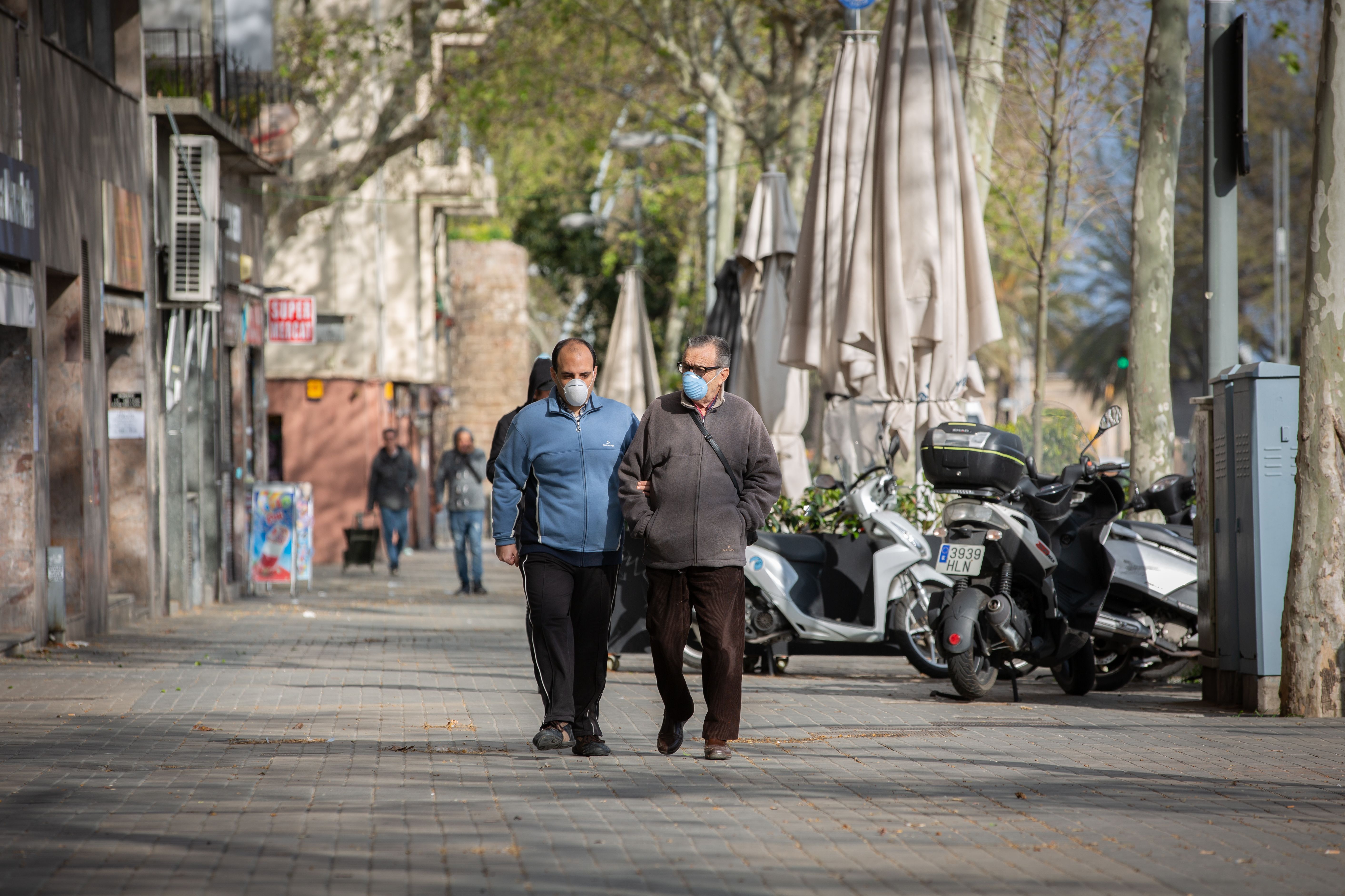 Dos homes caminen pels carrers de Barcelona amb una mascareta durant l'estat d'alarma pel coronavirus | Europa Press