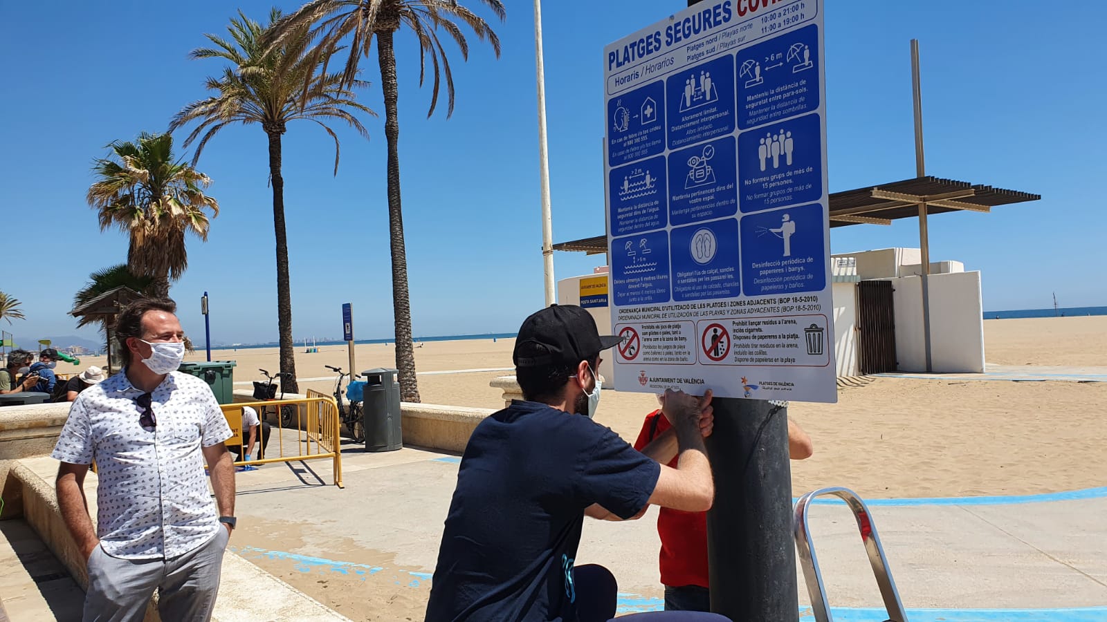 Un operario coloca un cartel donde se regulan las normas en las playas de Valencia | Ayuntamiento de Valencia