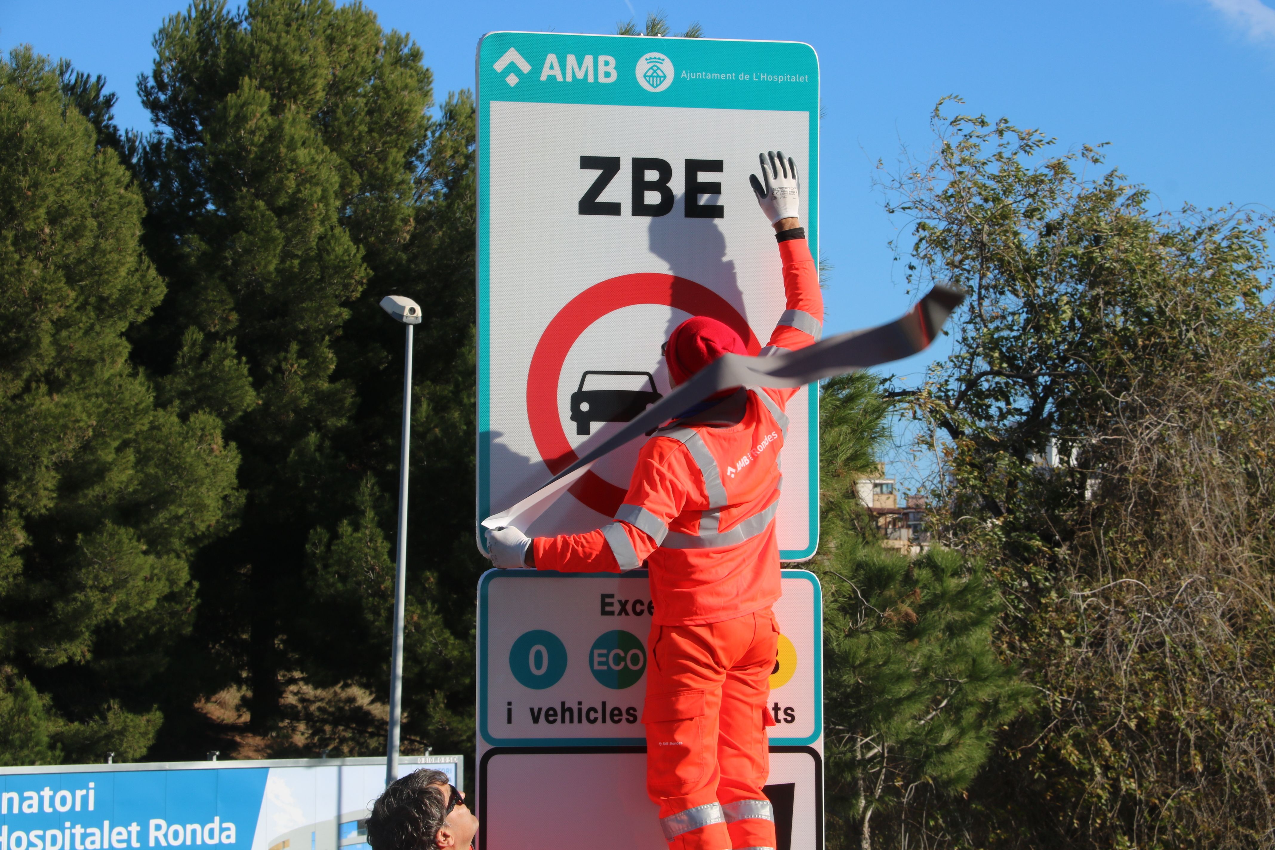 Unos operarios instalando una señal de la ZBE a la Hospitalet | ACN