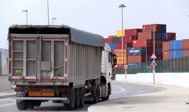 Un camió surt del port de Barcelona, amb contenidors per a exportacions al fons | ACN