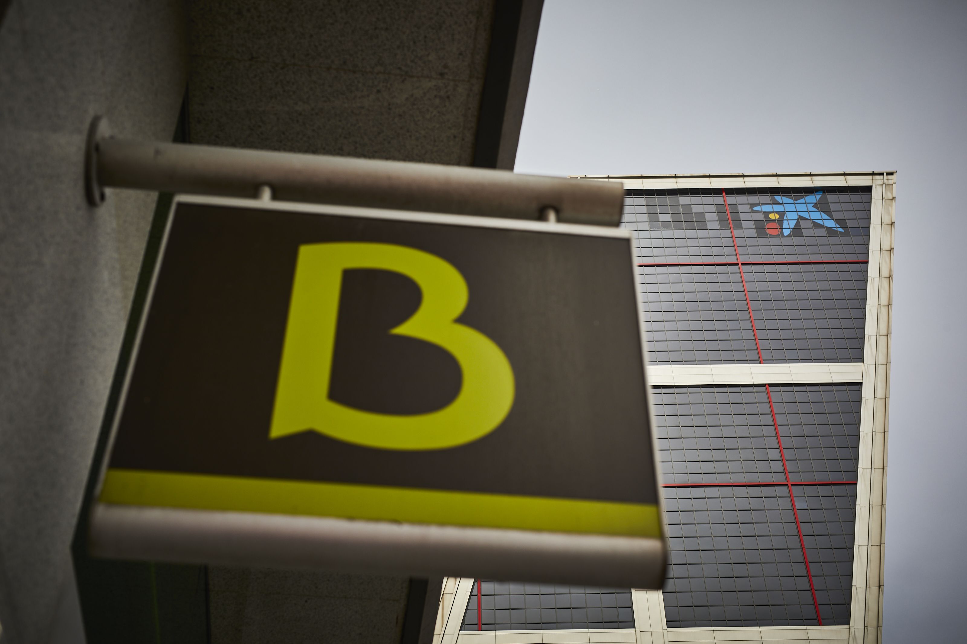 Una oficina de Bankia amb el logo de Caixabank de fons, en una imatge d'arxiu | Europa Press