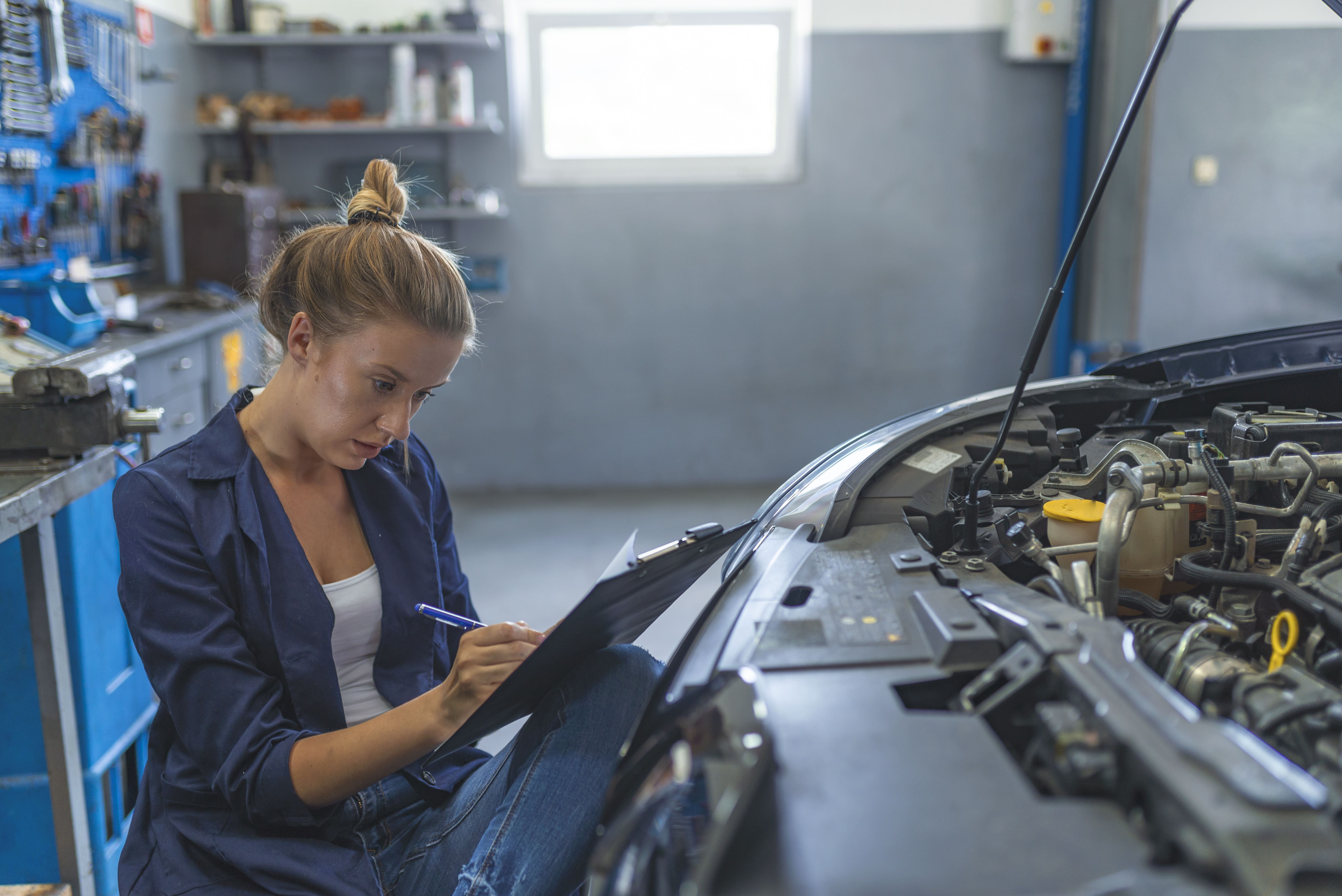 Mujer en un centro de servicio de reparación de automóviles | iStock