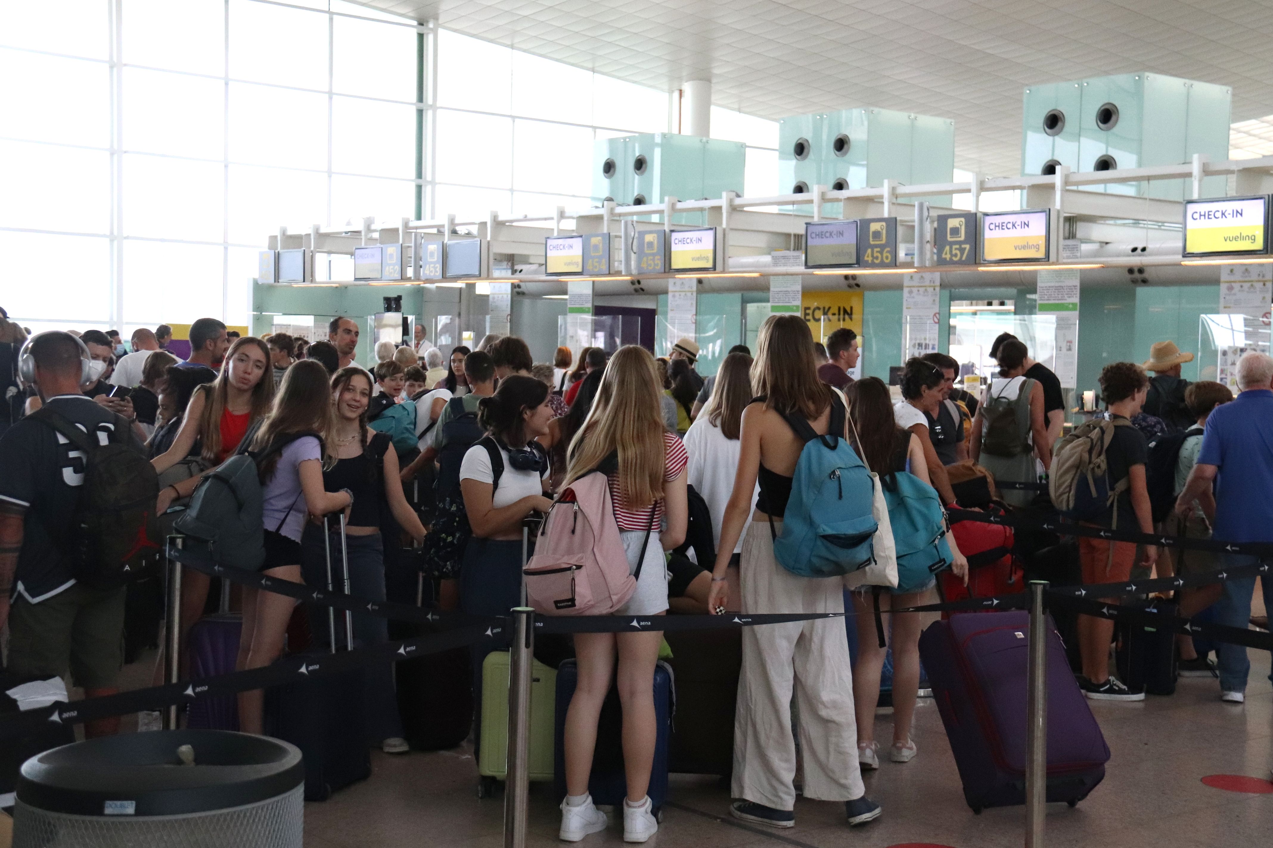 Grups de passatgers fent cua als taulells de facturació de Vueling de la T1 de l'aeroport del Prat | ACN