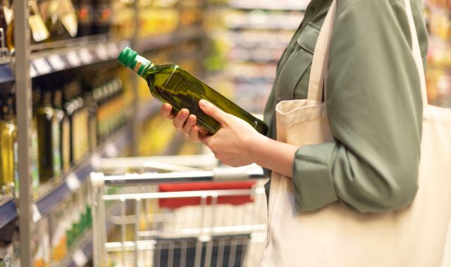 Una noia comprant oli a un supermercat català | iStock