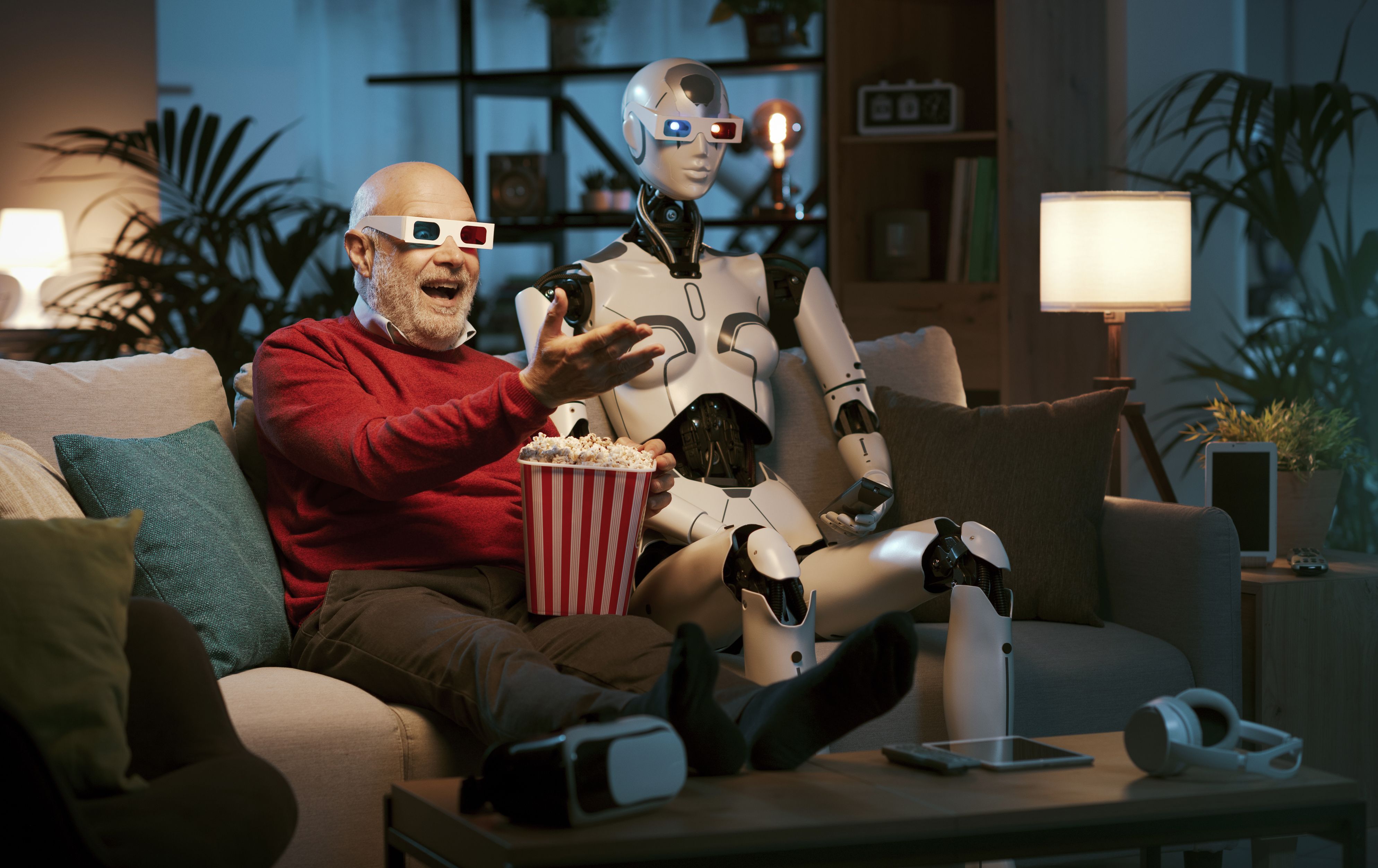 Imagen de archivo de un hombre y un robot mirando una película | iStock