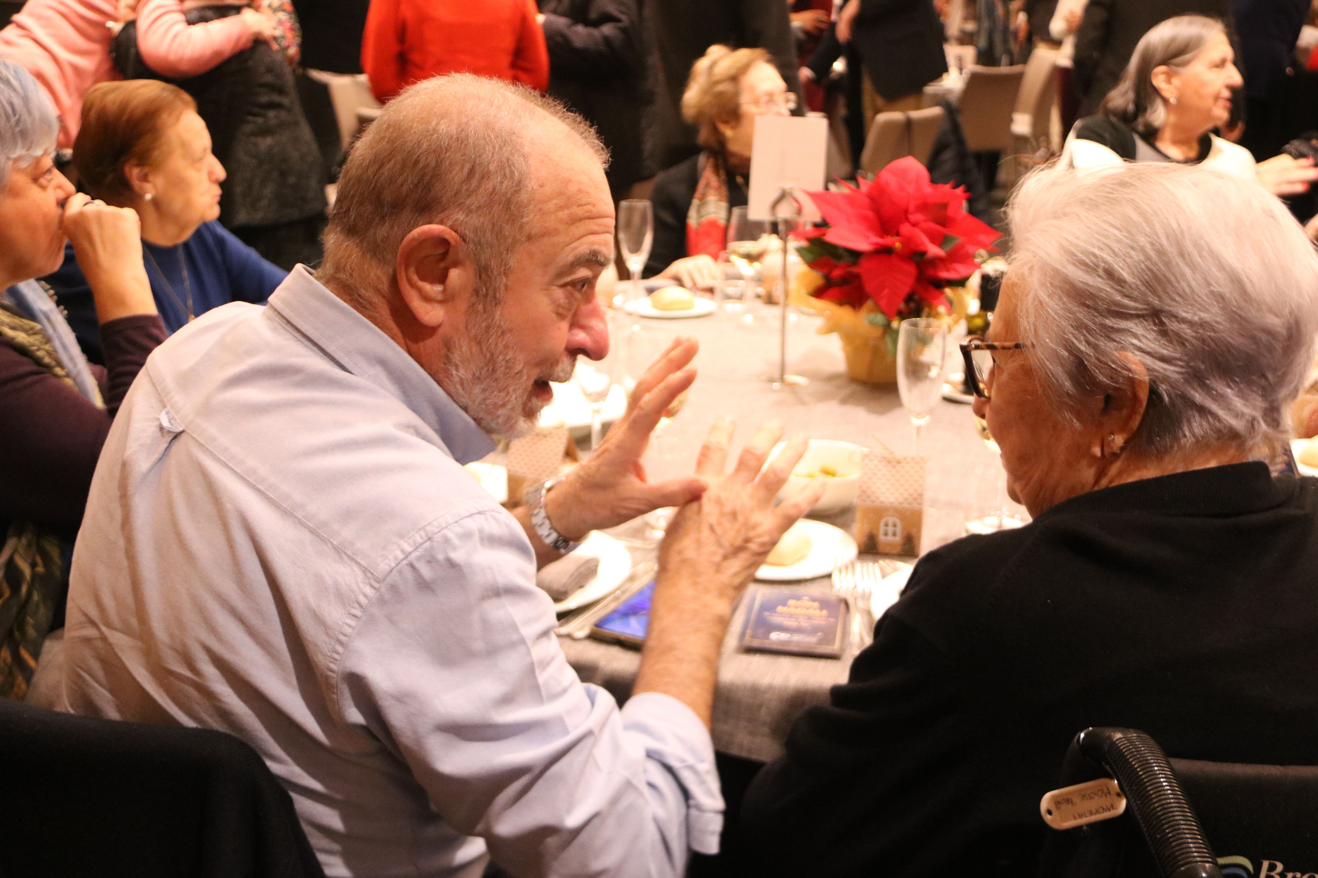 Personas que participan en la entidad Amics de la Gent Gran conversando durante la comida de Navidad | ACN