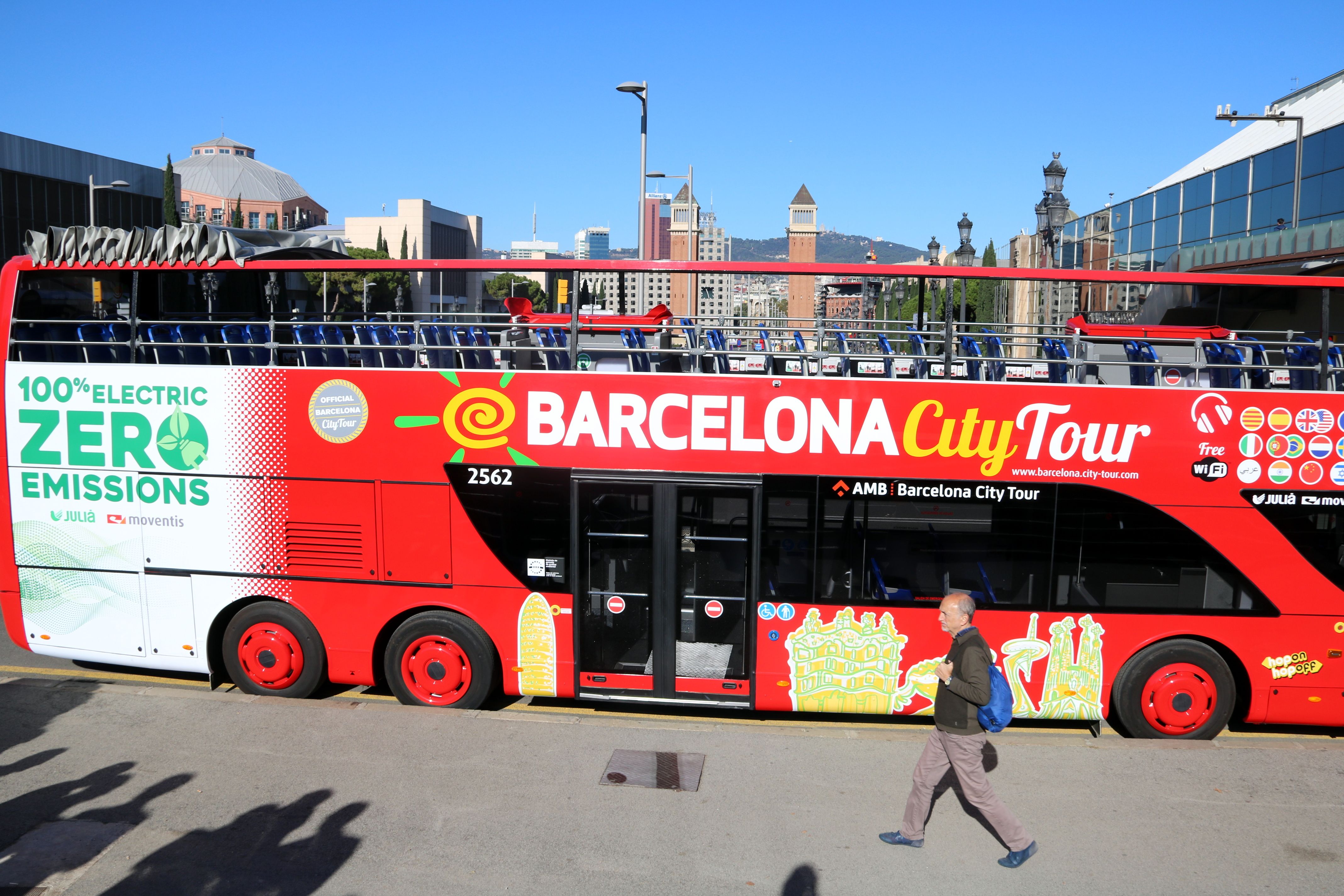 El bus turístic de doble pis 100% elèctric, amb les torres venecianes de la plaça Espanya de fons | ACN