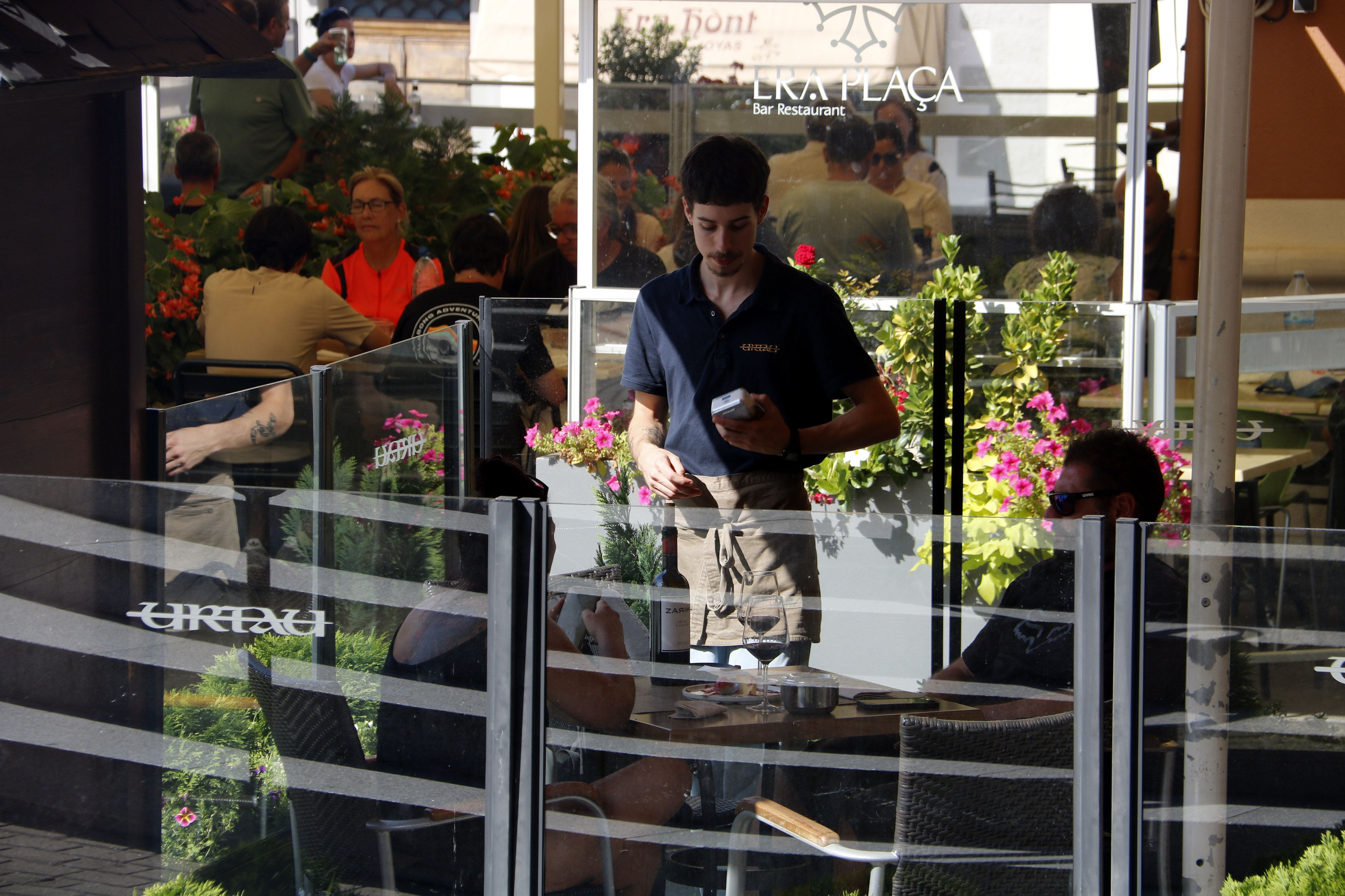 Un camarero cobrando a dos clientes en una terraza en Vielha | ACN