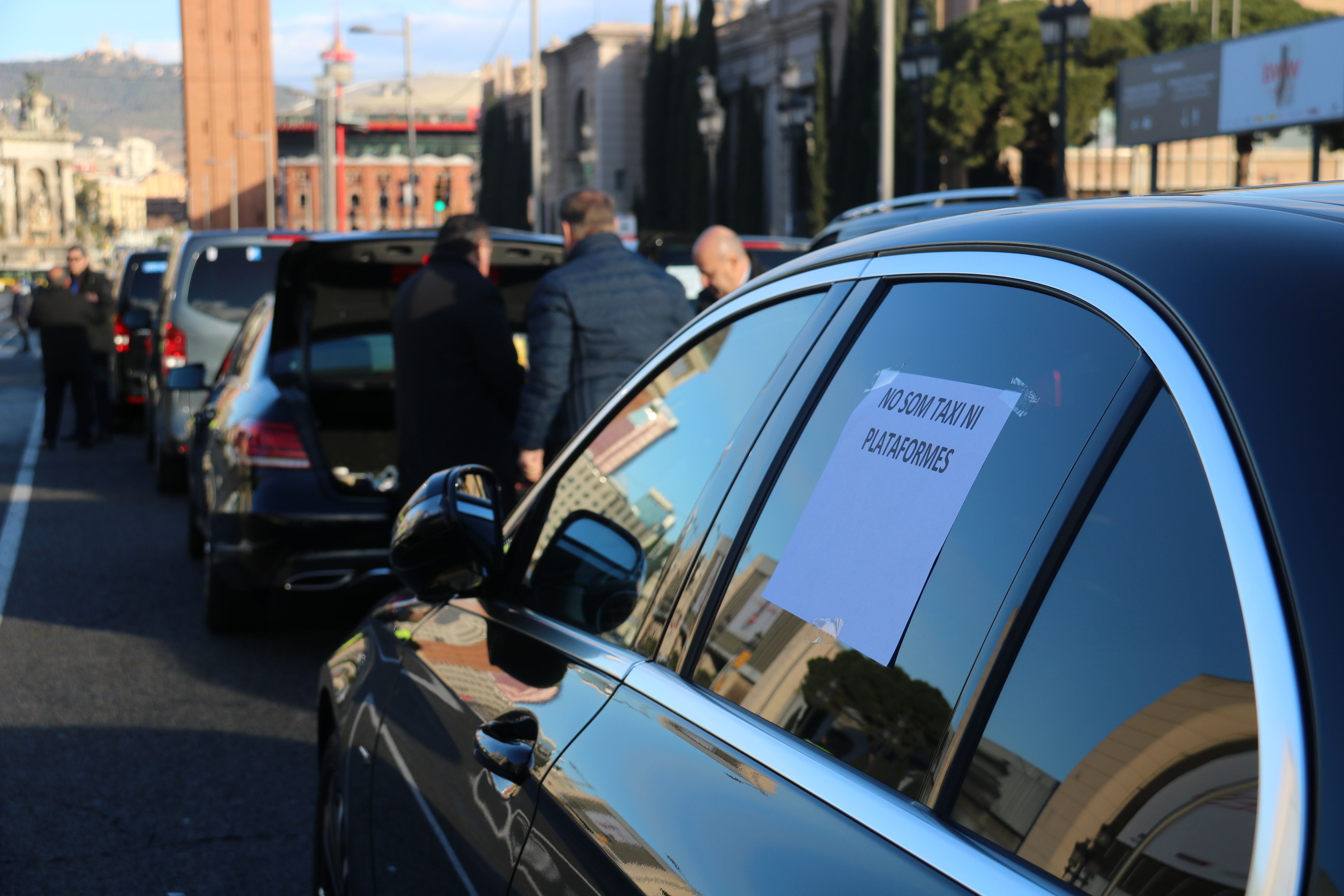 Un cartell a la finestra d'un cotxe amb llicència VTC a l'avinguda Maria Cristina abans de començar una marxa lenta per Barcelona | ACN