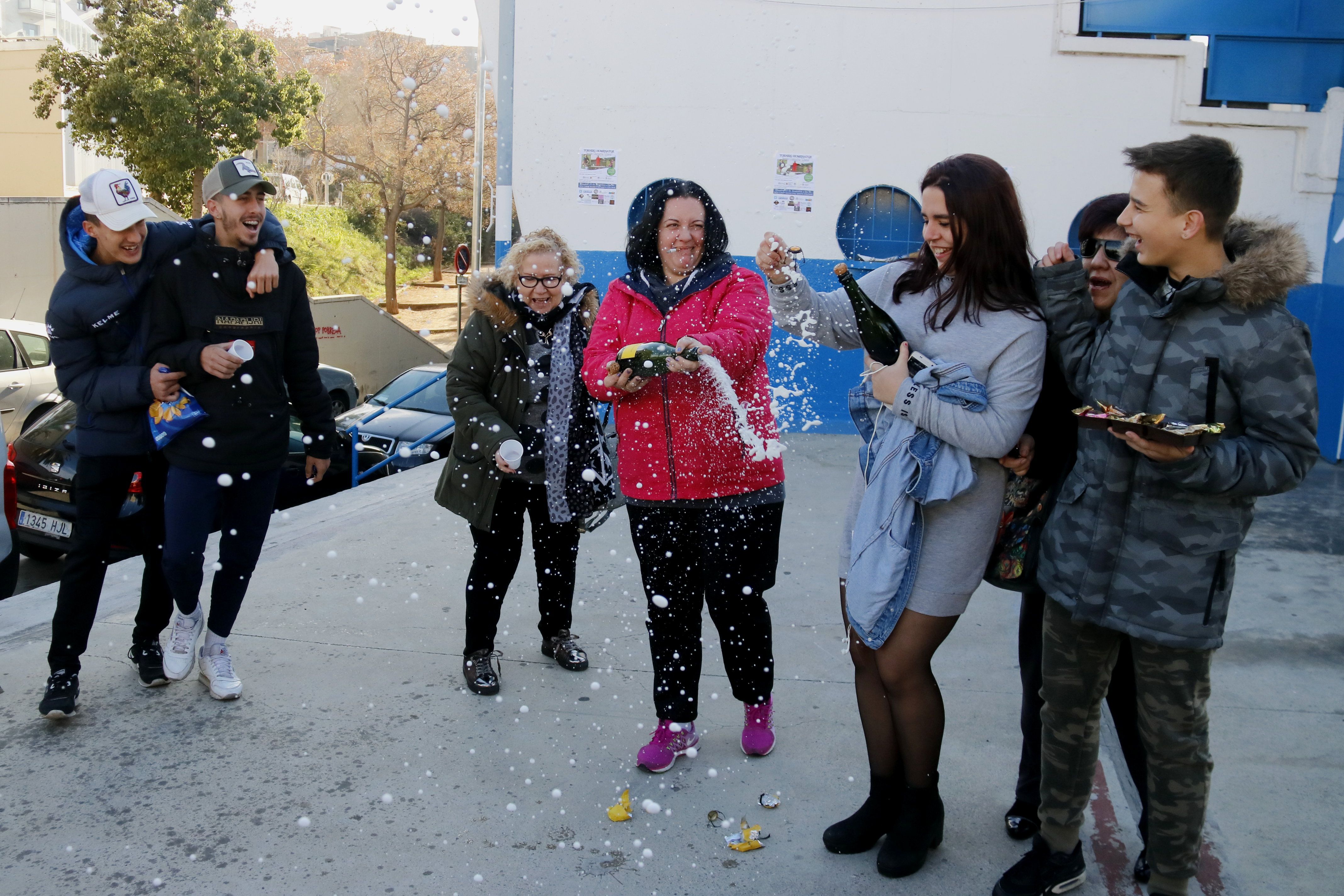 Veïns de Santa Coloma de Gramenet celebren amb cava el tercer premi de la Rifa de Nadal davant el camp de futbol de la Grama | ACN