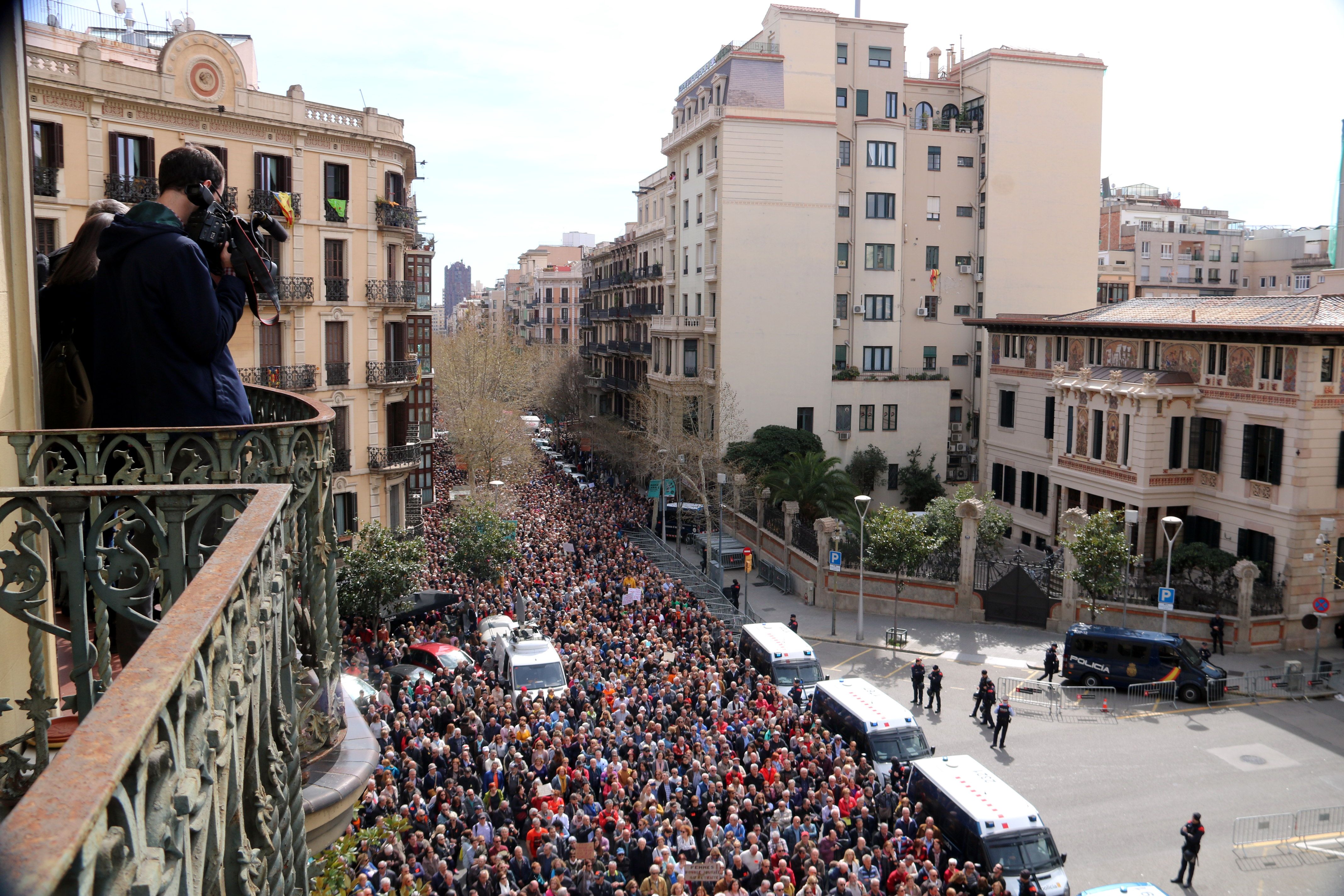 Un periodista gràfic gravant des d'un balcó la marxa de les pensions que recorre el carrer Roger de Llúria de Barcelona | ACN