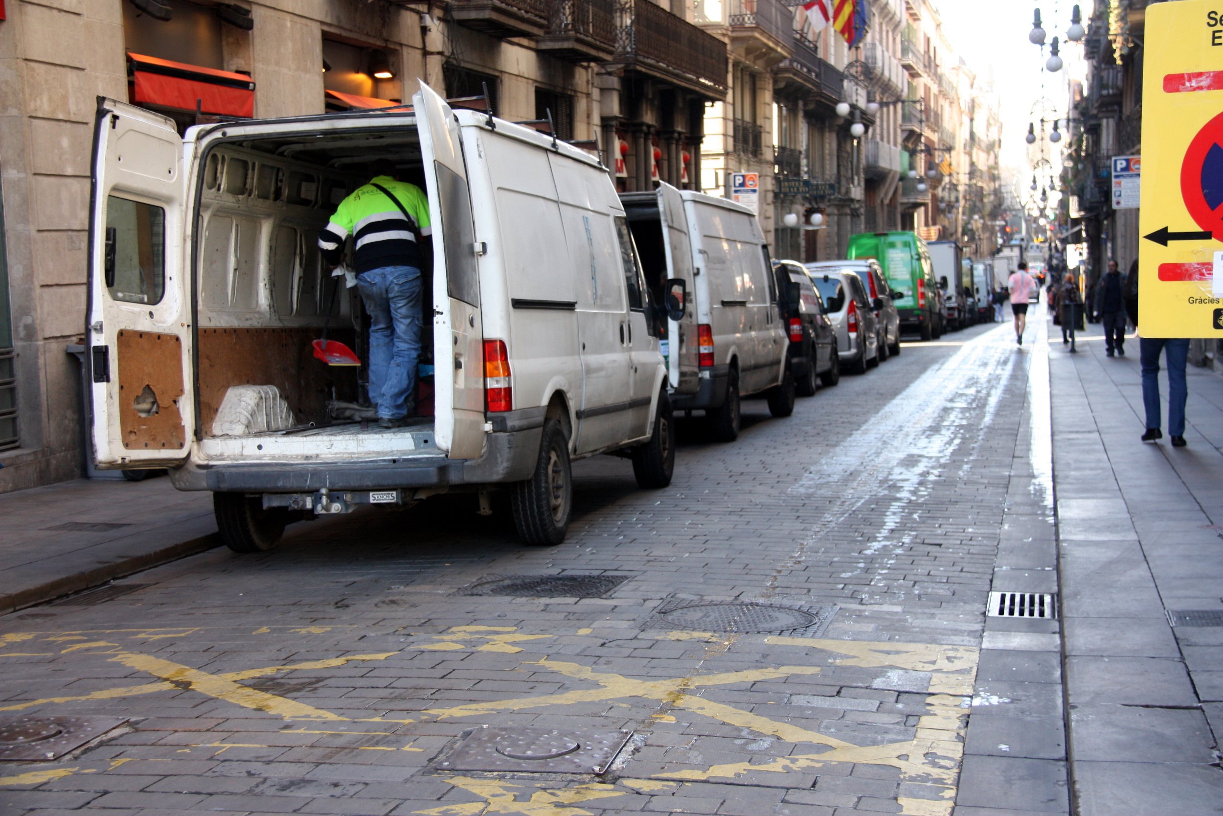 Furgoneta estacionada a una zona de càrrega i descarrega amb un transportista treballant